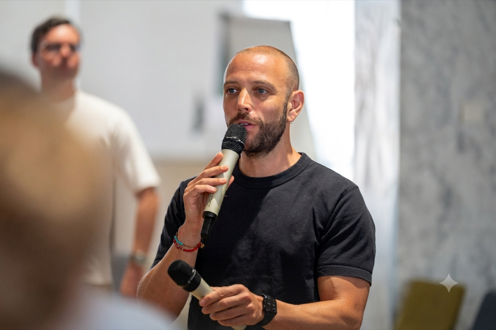 Alex speaking into a microphone at a workshop