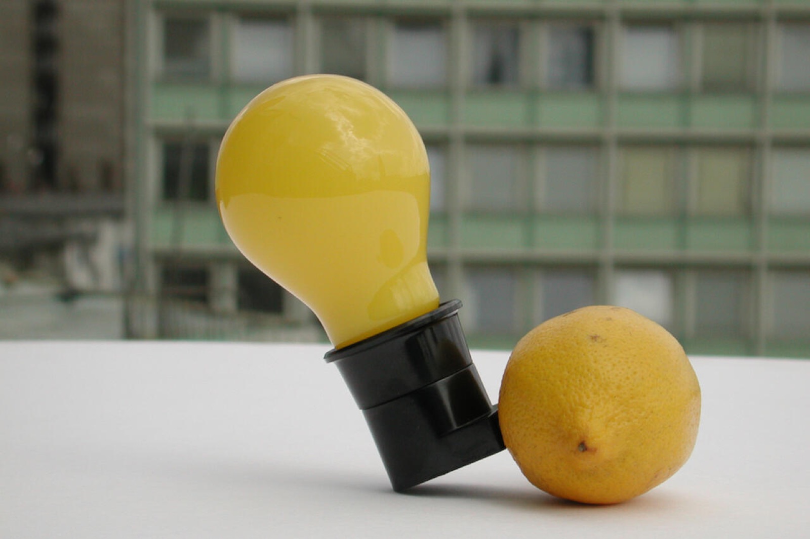 A yellow lightbulb and a lemon on a white surface
