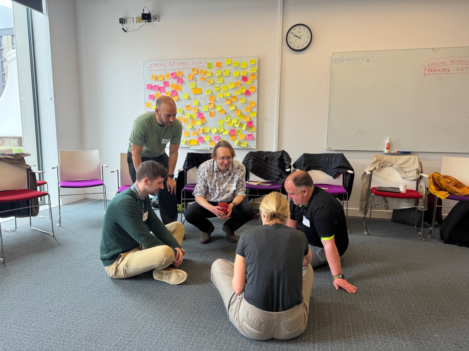 Participants sitting on the floor in front of a wall of post-it notes